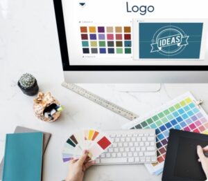 Ici, on voit un ordinateur où un logo figure sur l’écran avec plusieurs couleurs, la personne est en réflexion quant aux choix graphiques. 